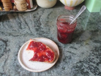 Description: strawberry jam on partially-eaten toast, jar of strawberry jam